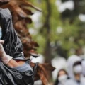 Juana Gomez, à esquerda, usa máscara, luvas, e um saco de lixo para se proteger da chuva na fila de espera em um centro de distribuição de alimentos durante a pandemia do coronavírus, no dia 9 de abril de 2020, em Van Nuys, na Califórnia.