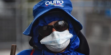 A municipal worker wears a face mask as a preventive measure against the spread of the novel coronavirus, COVID-19, as she sweeps the streets in the historic centre of Quito on March 25, 2020. - President Lenin Moreno on Tuesday called out Ecuadorans who flouted isolation measures -- including a daily curfew -- saying their actions amounted to "terrorism." (Photo by Rodrigo BUENDIA / AFP) (Photo by RODRIGO BUENDIA/AFP via Getty Images)