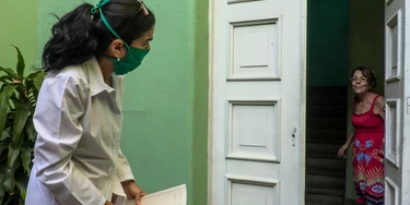 Cuban doctor Liz Caballero (L), interviews a woman as she goes door by door looking for possible cases of the novel coronavirus, COVID-19, in Havana on March 31, 2020. - As Cuba struggles under the weight of US sanctions, COVID-19 has given the country's medical sector the opportunity to export their services in the midst of the coronavirus pandemic. (Photo by Adalberto ROQUE / AFP) (Photo by ADALBERTO ROQUE/AFP via Getty Images)