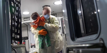 Paramédico segura bebê com febre após chegar de ambulância no hospital de Stamford, em 4 de abril.