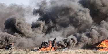 Manifestantes palestinos queimam pneus durante um protesto contra repetidos ataques nos pátios da Mesquita de Al-Aqsa, perto da cerca com Israel, a leste da Cidade de Gaza.