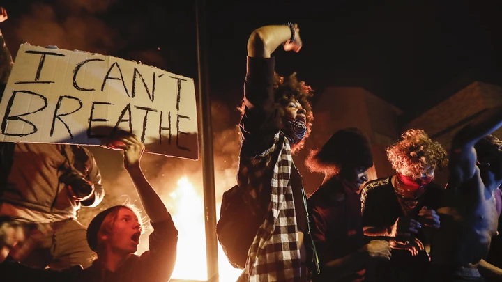 Protestors demonstrate outside of a burning Minneapolis 3rd Police Precinct, Thursday, May 28, 2020, in Minneapolis. Protests over the death of George Floyd, a black man who died in police custody Monday, broke out in Minneapolis for a third straight night. (AP Photo/John Minchillo)