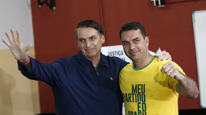 FILE - In this Oct. 7, 2018 file photo, then presidential frontrunner Jair Bolsonaro, left, and his son Flavio, acknowledge reporters at a polling station in Rio de Janeiro, Brazil. The son of Brazilian President-elect Jair Bolsonaro is denying wrongdoing in a case involving suspect bank transactions. According to a recent Financial Activities Control Council report, Flavio Bolsonaro's driver deposited various amounts between January 2016 and January 2017. On Thursday, Dec. 13, 2018, Flavio Bolsonaro posted on Twitter that he had “done nothing wrong.” (AP Photo/Silvia Izquierdo, File)