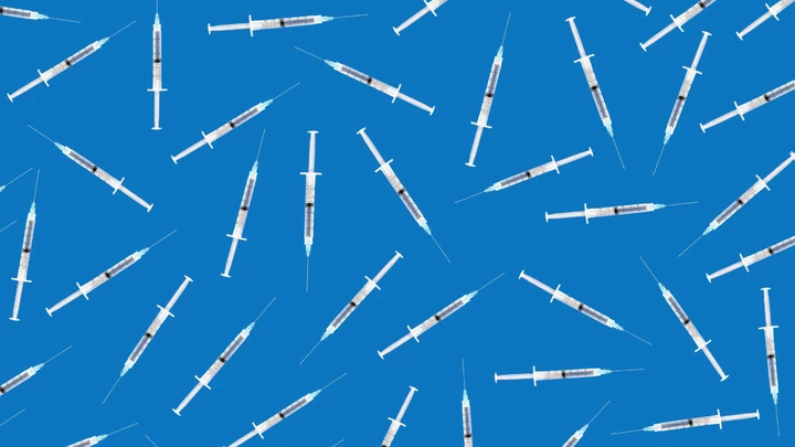 Many medical syringes scattered on blue background