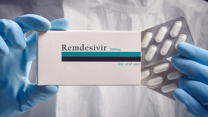 Medical worker holding pack of remdesivir pills