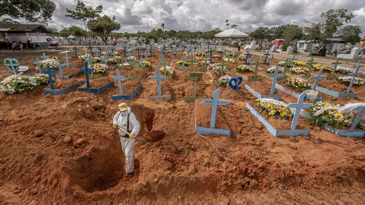 Worker wearing personal protective equipment (PPE) digs a grave at a cemetery in Manaus, Brazil, on Tuesday, Jan. 19, 2021. Severe oxygen shortages at hospitals in Brazil's Amazon prompted local authorities to impose a curfew and airlift patients to other states to deal with the onslaught of a second coronavirus wave. Photographer: Jonne Roriz/Bloomberg via Getty Images
