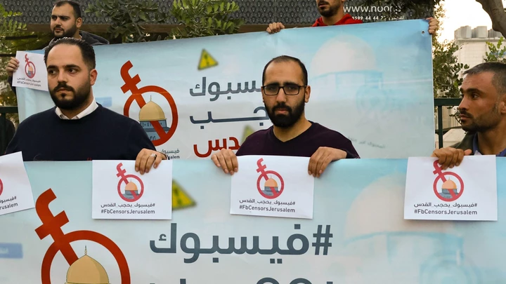 Na cidade ocupada de Hebron, na Cisjordânia, ativistas e jornalistas palestinos seguram faixas de protesto contra o que consideram censura de conteúdo palestino pelo Facebook, em 24 de novembro de 2021.