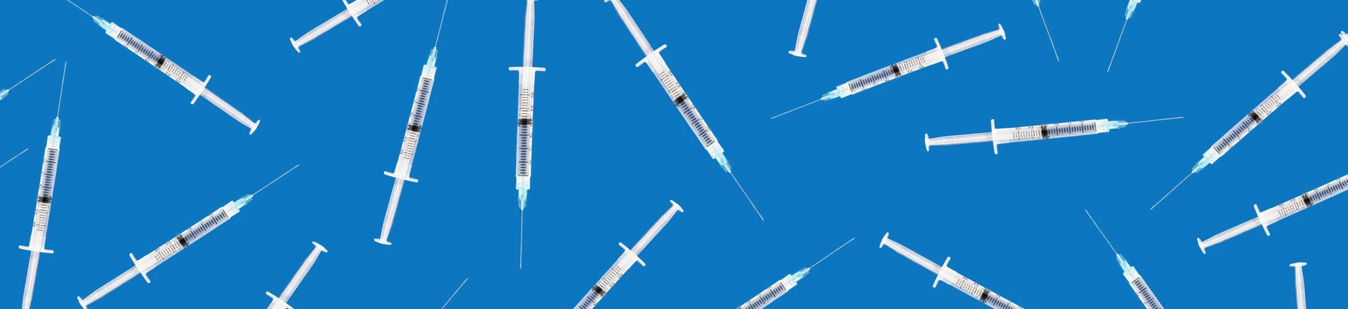 Many medical syringes scattered on blue background