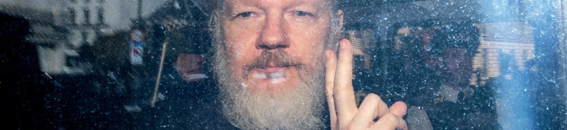 Julian Assange gesticula para a mídia de um veículo da polícia em sua chegada ao Tribunal Magistrados de Westminster, em 11 de abril de 2019 em Londres.