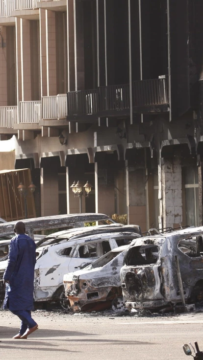 As forças de segurança ficam em frente ao exterior queimado do Splendid Hotel em Ouagadougou, Burkina Faso, em 16 de janeiro de 2016, um dia depois de um ataque da Al Qaeda ter matado 30 pessoas em um restaurante do outro lado da rua.