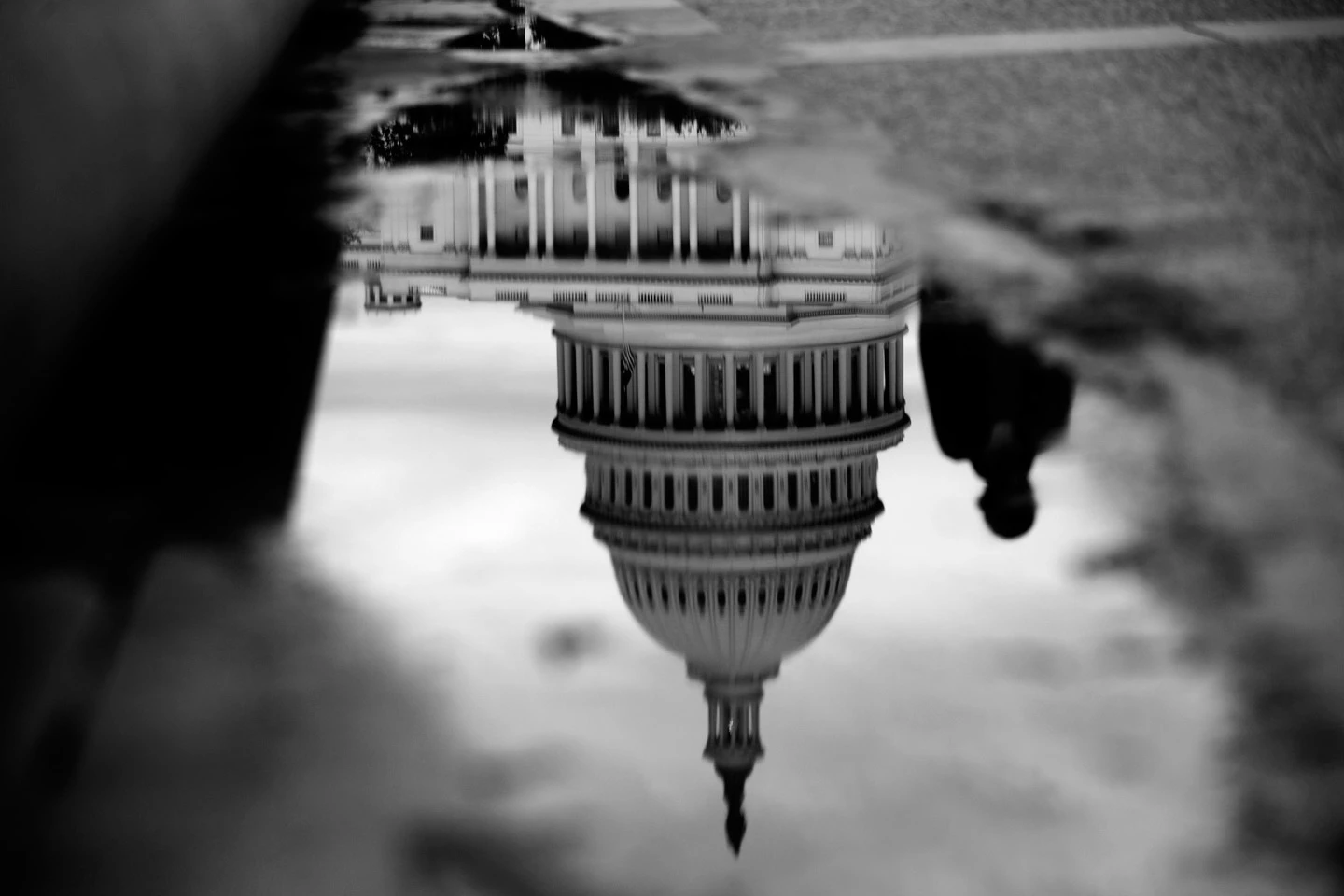 O Capitólio dos Estados Unidos refletido em uma poça junto do Espelho de Água do Capitólio, em Washington, D.C., Estados Unidos, na terça-feira, 15 de outubro de 2013. Hoje à noite, a Câmara rejeitou a votação de um plano fiscal que praticamente não inclui nenhuma das condições iniciais dos Republicanos para pôr fim à paralisação governamental de 15 dias e aumentar o teto da dívida, disse o Congressista Representante Pete Sessions, presidente do Comitê de Regras da Câmara. Fotógrafo: Andrew Harrer/Bloomberg via Getty Images