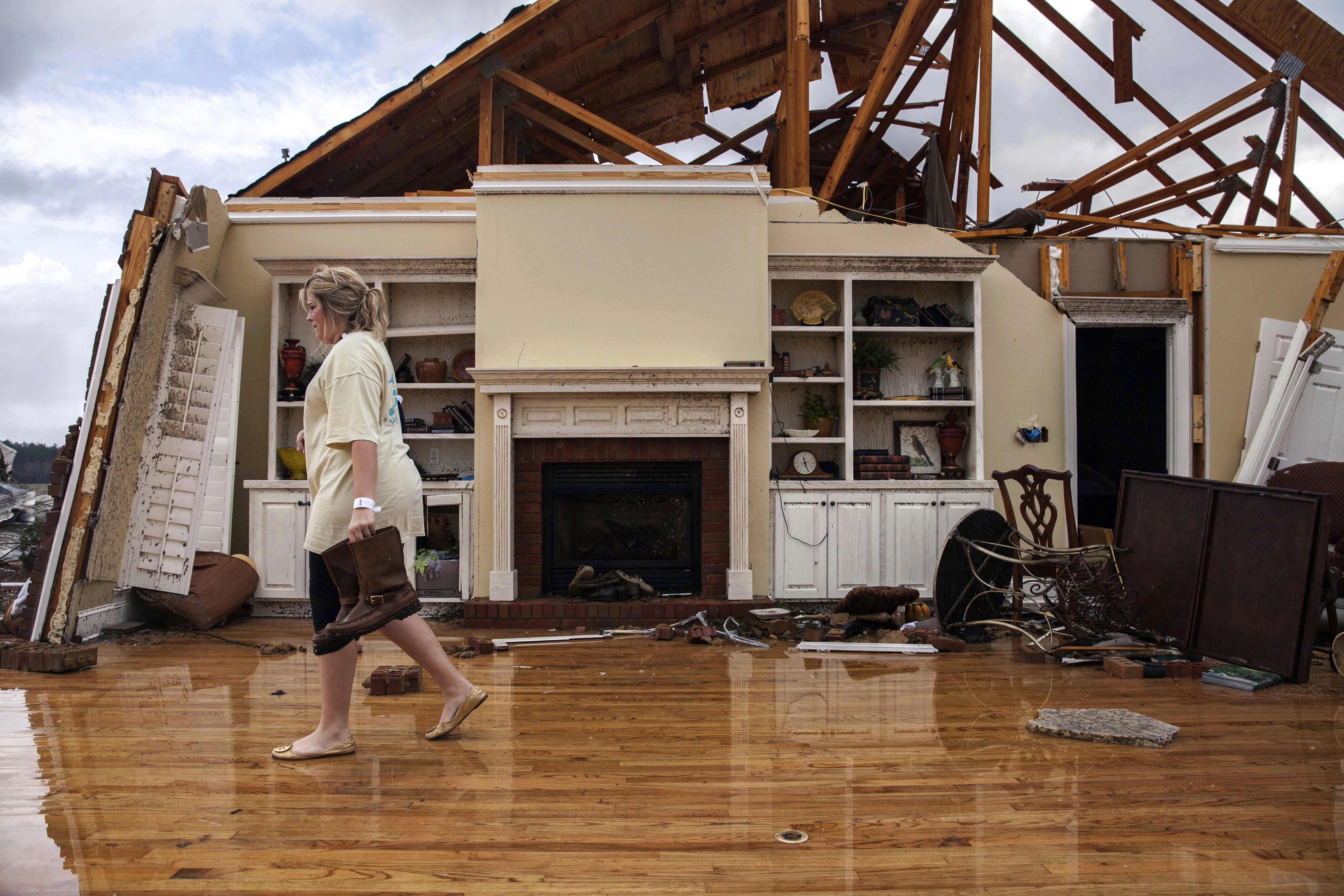 Jenny Bullard carrega um par de botas de sua casa que foi destruída por um tornado. Domingo, 22 de janeiro de 2017. Adel, Ga. O governador da Georgia, Nathan Deal, declarou estado de emergência em diversos municípios, incluindo Cook, onde ocorreram mortes, ferimentos e danos graves durante as tempestades do fim de semana. (AP Photo/Branden Camp)