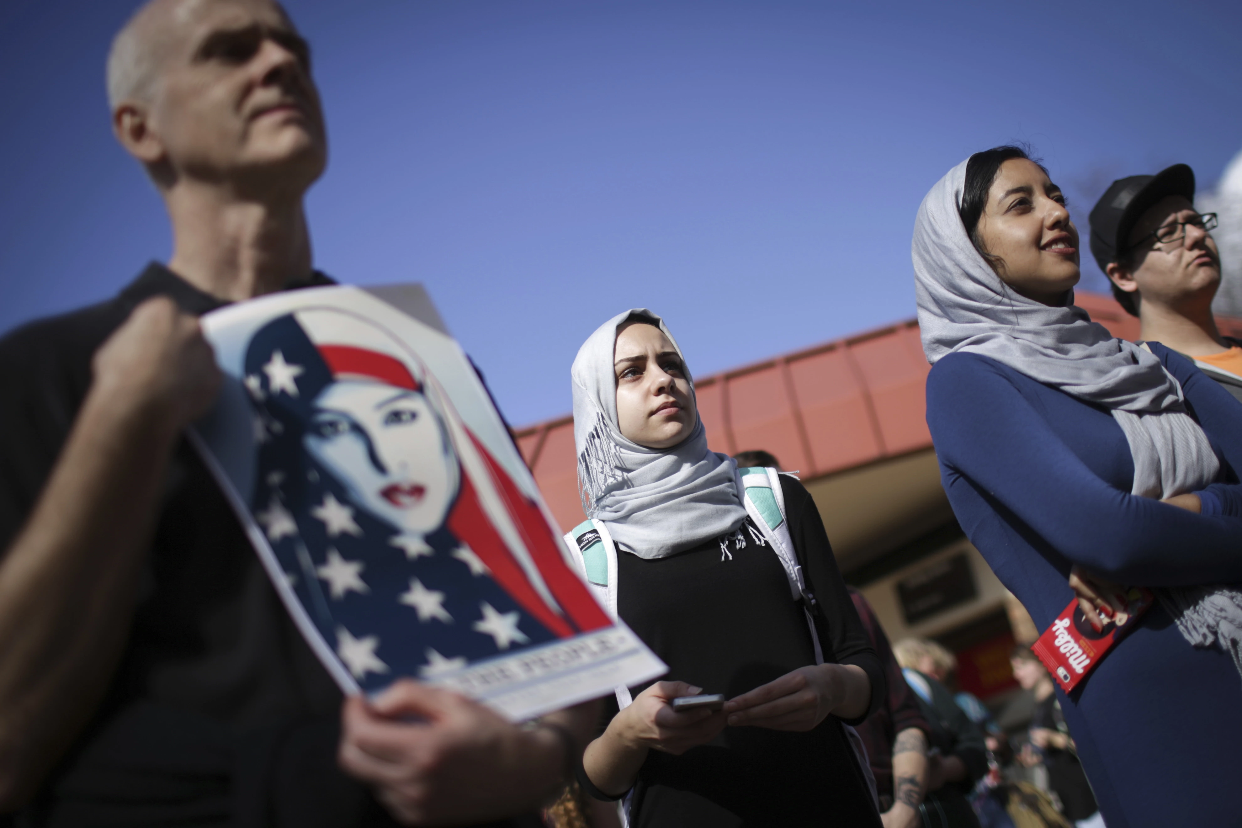 Mae Eldahshoury, centro, ouve discurso que questiona as políticas e práticas potencialmente discriminatórias do Presidente Trump. Universidade da Georgia, EUA. Sexta-feira, 20 de janeiro de 2017. Eldahshoury, da Aliança de Alunos Muçulmanos, veio ao protesto para apoiar a todos que possam ser afetados pelo posicionamento de Trump quanto à proibição da entrada de muçulmanos. (John Roark/Athens Banner-Herald via AP)