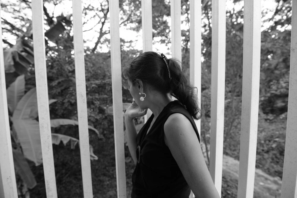 A Honduran mother looks out from a refuge for families seeking asylum in Tapachula, Chiapas. Gang members killed her husband, a police officer, six years ago. They demanded she hand over half of the money she earned selling food on the street, then later insisted her 13-year-old son join the gang or his 15-year-old sister become their girlfriend, so the family fled.They now live in a shelter for asylum-seekers as their application for refugee status is processed. They're grateful for the refuge, but the donated food is often scarce and they are allowed to leave just once a day and must be back by 6:00PM. They are terrified that gang members will spot them, as the city is full of migrants from Honduras.