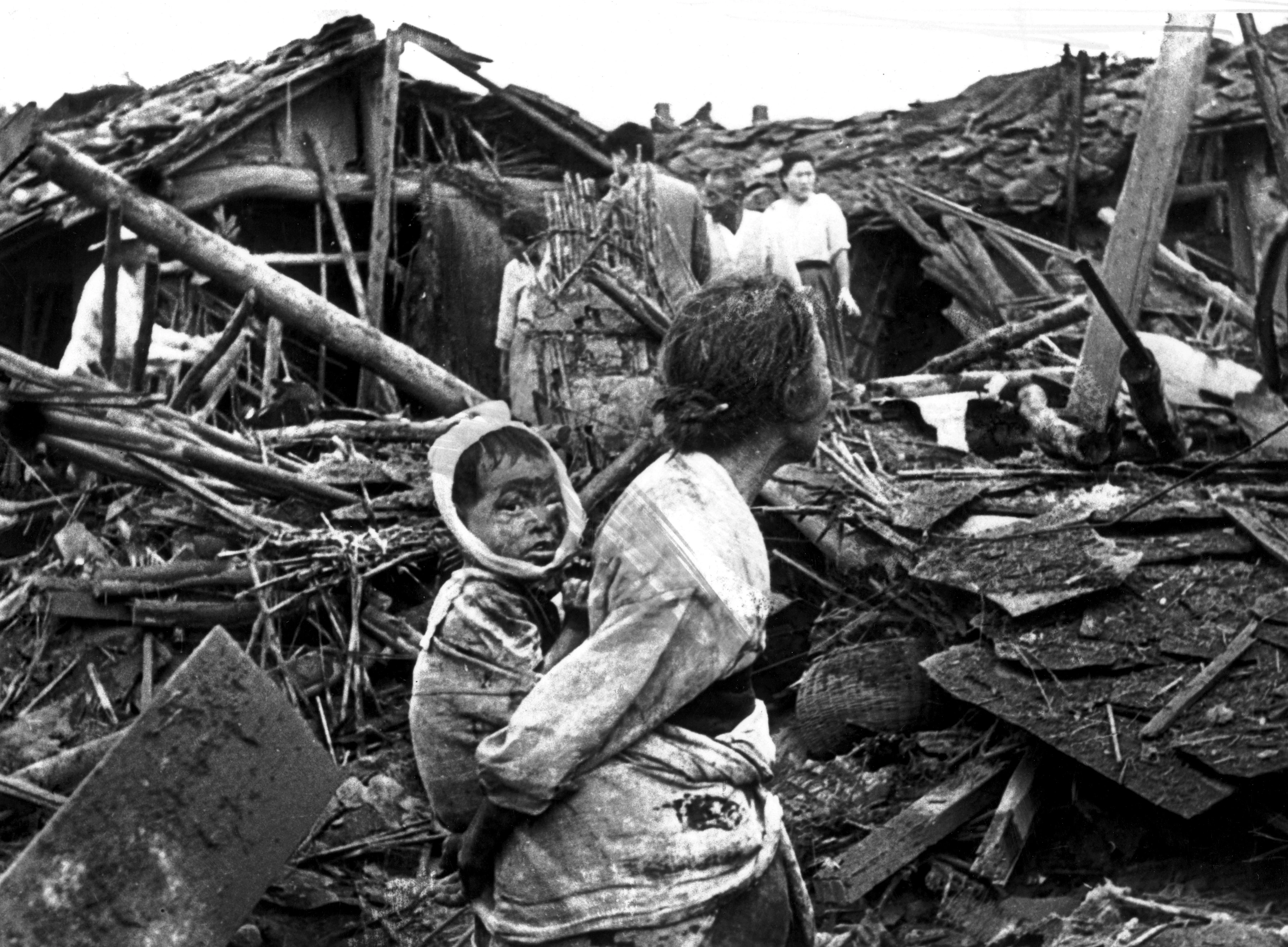 circa 1950: An elderly woman and her grandchild wander among the debris of their wrecked home in the aftermath of an air raid by U.S. planes over Pyongyang, the Communist capital of North Korea. (Photo by Keystone/Getty Images)
