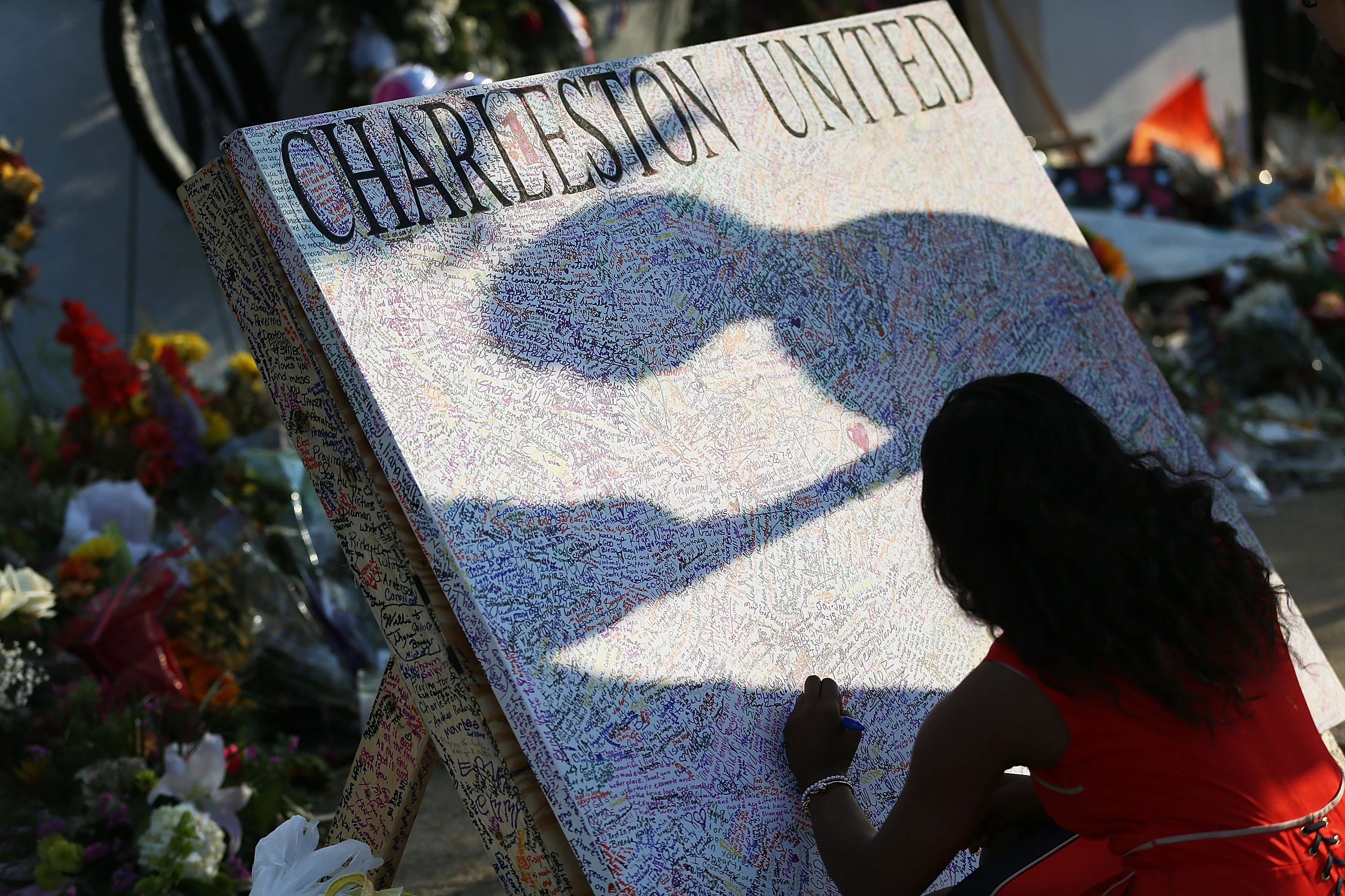 CHARLESTON, SC - JUNE 22:  Alana Simmons leaves a message on a board set up in front of the Emanuel African Methodist Episcopal Church after a mass shooting at the church killed nine people, on June 22, 2015. 21-year-old Dylann Roof is suspected of killing nine people during a prayer meeting in the church in Charleston, which is one of the nation's oldest black churches. (Photo by Joe Raedle/Getty Images)