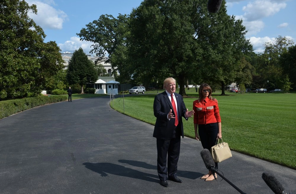 US President Donald Trump speaks about Hurricane Irma watched by First Lady Melania Trump upon return to the White House in Washington, DC on September 10, 2017. Trump returned to Washington after spending the weekend at the Camp David presidential retreat. / AFP PHOTO / MANDEL NGAN (Photo credit should read MANDEL NGAN/AFP/Getty Images)