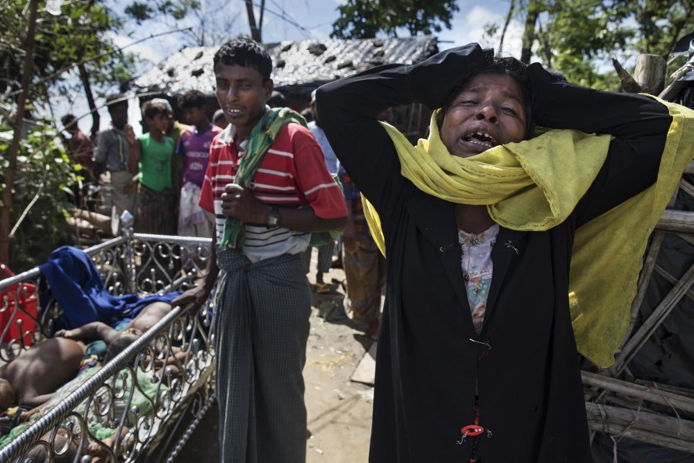 SHAH PORIR DWIP ISLAND, BANGLADESH - OCTOBER 9:  (EDITORS NOTE: Image contains graphic content.) Madia Khatun, a relative, grieves next to the bodies of 5 children,  after an overcrowded boat carrying Rohingya fleeing Myanmar capsized overnight killed around 12 people including five children on October 9, on Shah Porir Dwip Island, Cox's Bazar, Bangladesh.  Well over a half a million Rohingya refugees have fled into Bangladesh since late August during the outbreak of violence in Rakhine state causing a humanitarian crisis in the region with continued challenges for aid agencies. (Photo by Paula Bronstein/Getty Images)