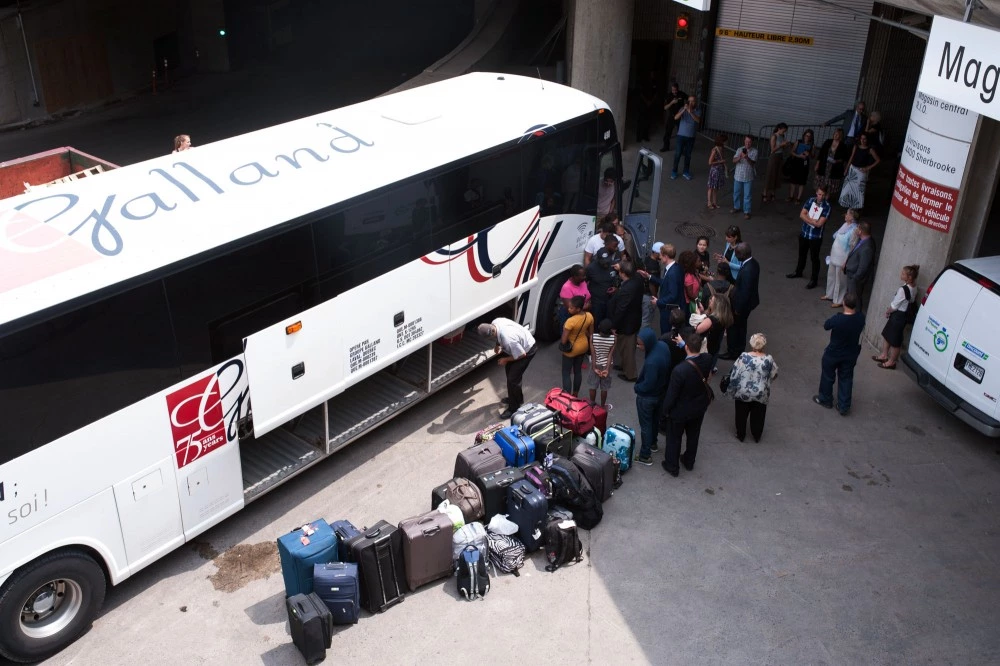 A bus of Haitian asylum seekers from the United States arrives at the Olympic Stadium in Montreal, Quebec on August 3, 2017. / AFP PHOTO / Catherine Legault        (Photo credit should read CATHERINE LEGAULT/AFP/Getty Images)