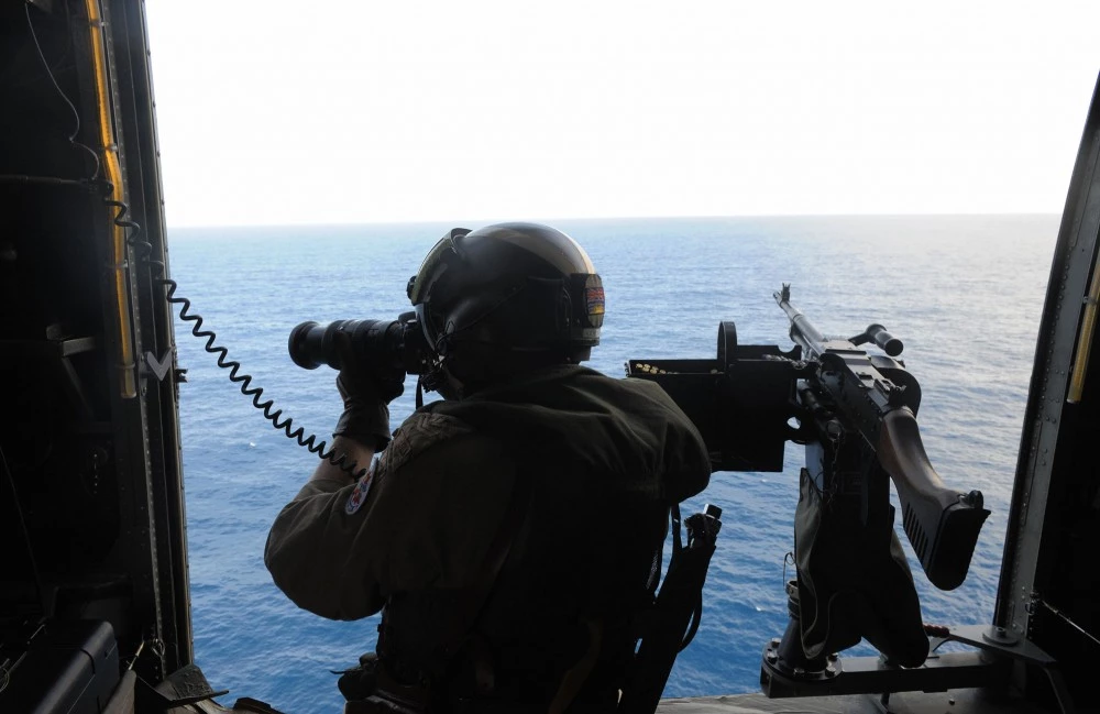 A Canadian Navy sailor on board a helicopter patrols the waters off the coast of Somalia as they escort a World Food Programme (WFP) ship on September 17, 2008, providing an anti-pirate escort for the ship taking food aid to Somalia. The UN Security Council in June adopted a resolution authorising foreign warships to enter Somalia's territorial waters with the government's consent to combat pirates, though it has yet to be implemented. European foreign ministers agreed to set up a special unit to coordinate the fight against piracy off Somalia, raising the possibility of a EU naval mission to the region. Ninety percent of food aid is delivered to the Horn of Africa country by ship, the last lifeline for starving millions since insurgents armed with surface-to-air missiles make air and road deliveries too dangerous. AFP PHOTO/SIMON MAINA (Photo credit should read SIMON MAINA/AFP/Getty Images)