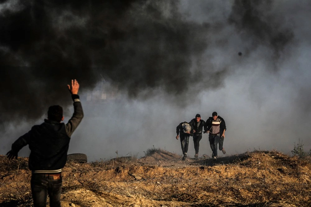 Palestinians protesters run for cover from Israeli tear gas during clashes with Israeli troops along the border between Israel and Gaza Strip, in the eastern Gaza Strip, 01 April 2018. According to reports, nine Palestinians were injured during the clashes along the border with Israel. Protesters plan to call for the right of Palestinian refugees across the Middle East to return to homes they fled in the war surrounding the 1948 creation of Israel. (Photo by Momen Faiz/NurPhoto/Sipa USA)(Sipa via AP Images)