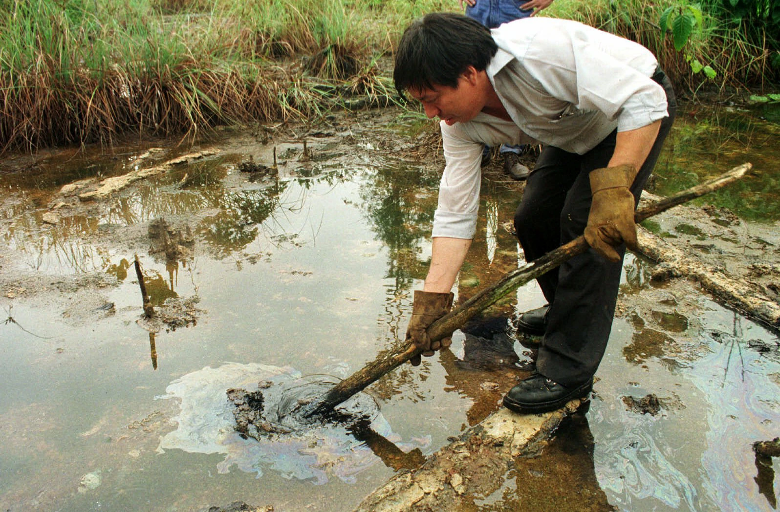 Manuel Silva a peasant  shows an oil spill in Lago Agrio,in Ecuador eastern Amazonian jungles,Monday,Dec.14,1998. Ecuadorean Indians have suited Texaco Inc.  accusing the company of turning the region's rain forests into a "toxic waste dump" by drilling for oil.(AP Photo/Dolores Ochoa).