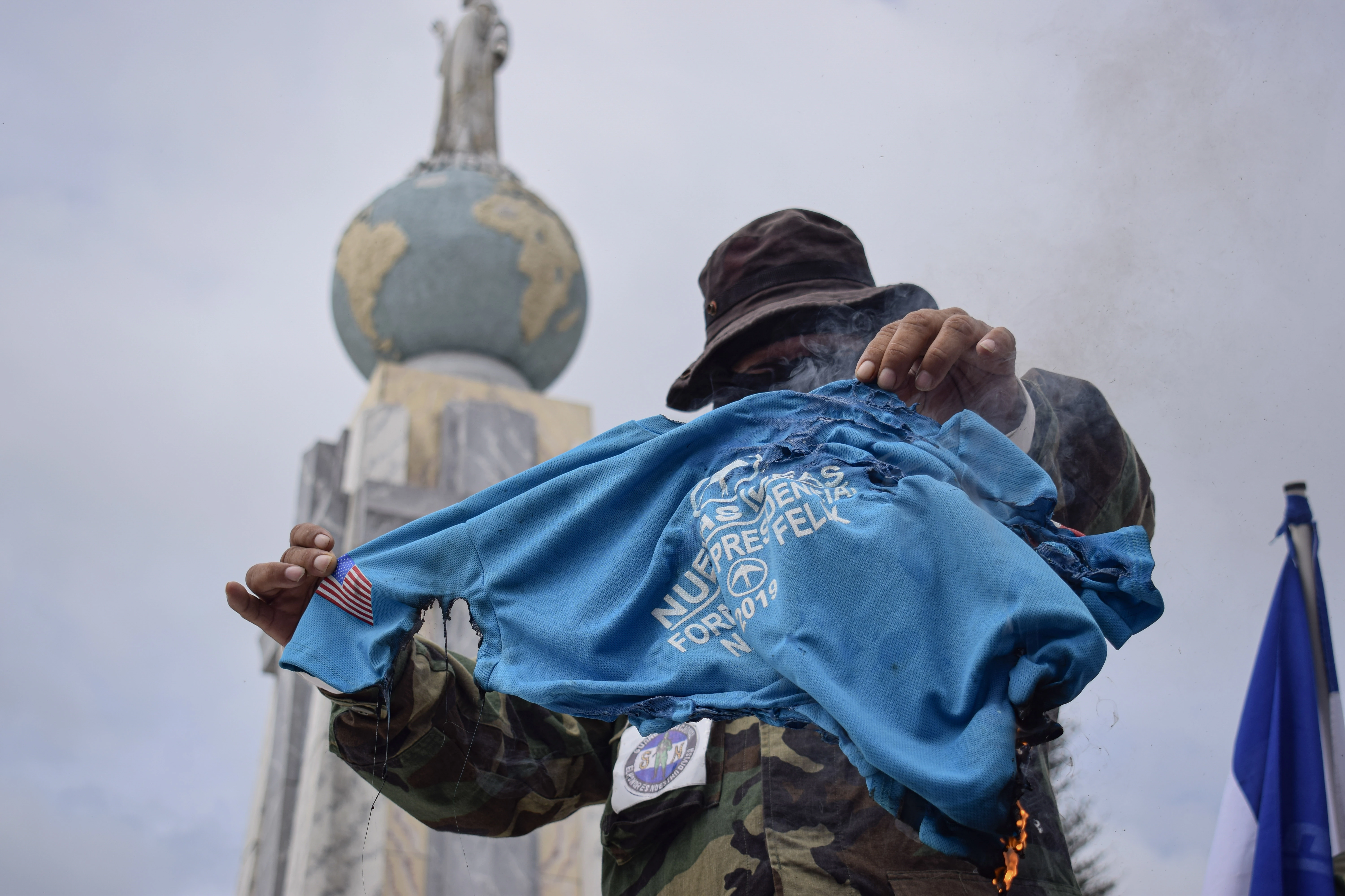 SAN SALVADOR, EL SALVADOR - JUNE 01: A protestor holds up a burning Nayib Bukele campaign shirt during a demonstration against the Nayib Bukele administration at the Plaza Salvador del Mundo on June 1, 2022 in San Salvador, El Salvador. Members of social organizations protest against the third anniversary of the government of President Nayib Bukele. (Photo by Kellys Portillo/APHOTOGRAFIA/Getty Images)