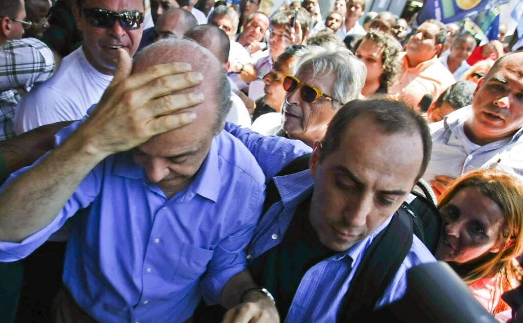 Brazil's presidential candidate Jose Serra (L) of the Social Democratic Party of Brazil protects his head after being "knocked silly" by a thrown object, during a rally in Campo Grande, 55 km from Rio de Janeiro's downtown, on October 20, 2010. Serra and rival Dilma Rousseff of the ruling Workers' Party, will face on October 31 in the run-off election. AFP PHOTO/Cesar Da Silva (Photo credit should read CESAR DA SILVA/AFP/Getty Images)