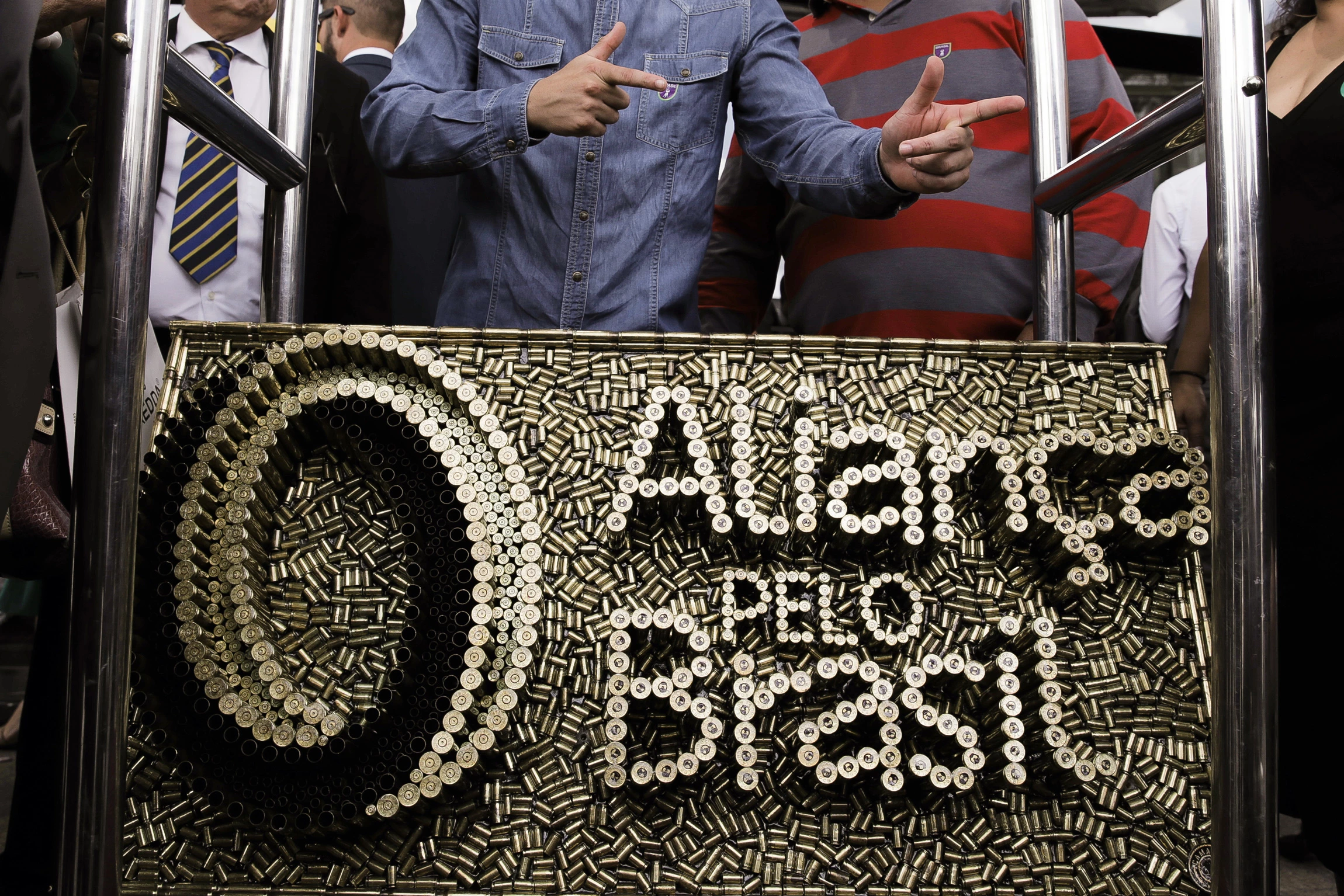 Apoiadores posam para fotos com uma obra com o nome e símbolo do partido Aliança pelo Brasil, feito com cartuchos de balas.