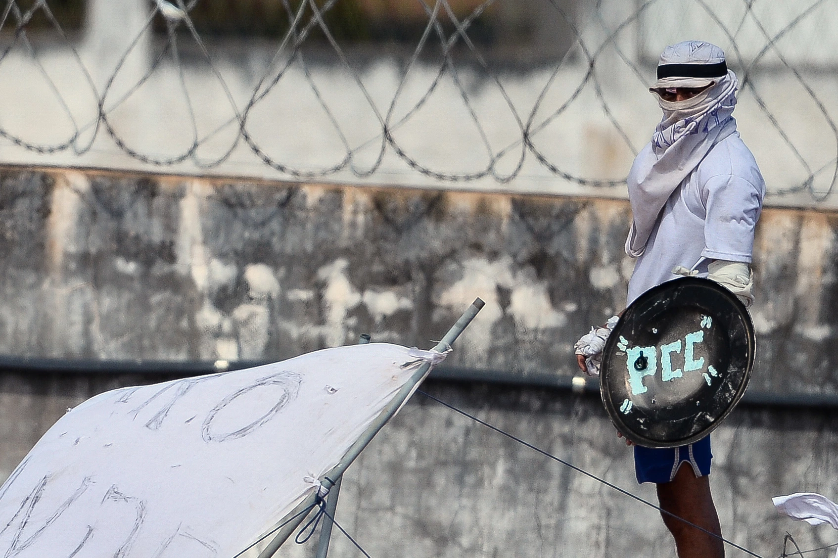 An inmate with his face covered stands on the prison roof during a rebellion in Alcacuz Penitentiary Center near Natal, Rio Grande do Norte state, northeastern Brazil on January 16, 2017.The latest in a string of brutal prison massacres involving suspected gang members in Brazil has killed 26 inmates, most of whom were beheaded. The bloodbath erupted Saturday night in the overcrowded Alcacuz prison in the northeastern state of Rio Grande do Norte. Similar violence at other jails in Brazil left around 100 inmates dead in early January. / AFP / ANDRESSA ANHOLETE (Photo credit should read ANDRESSA ANHOLETE/AFP/Getty Images)