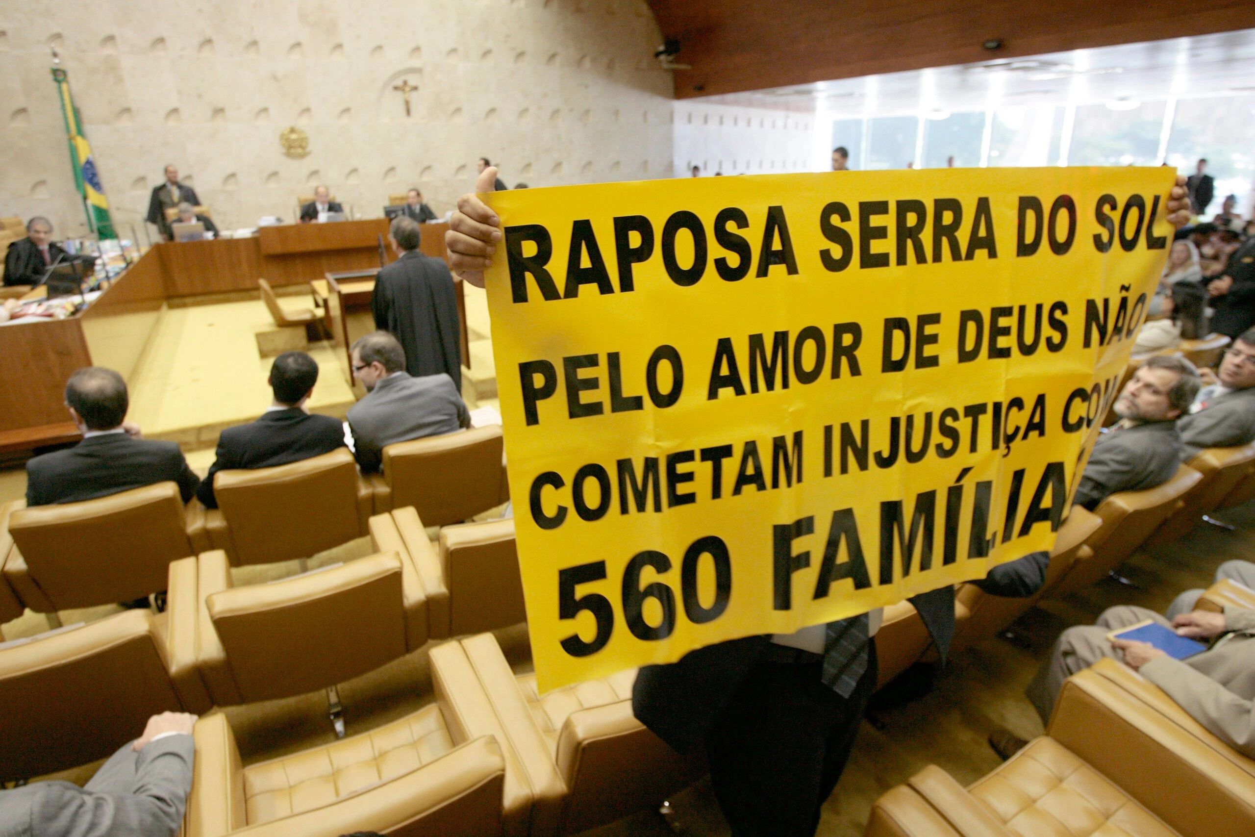 A representative of a group of farmers who oppose a resolution of Brazil's Supreme Court, confirming that the Raposa Serra do Sol reservation in northern Brazil must remain intact, holds a sign during a court's session in Brasilia, Thursday, March 19, 2009. The court ruled Thursday that the reservation must remain intact, a ruling seen as bolstering indigenous rights, and which sets an important precedent for laying out and protecting the boundaries for many Indian reserves in Brazil.The sign reads in Portuguese: "Raposa Serra do Sol, for the love of God don't commit injustice for 560 families".(AP Photo/Eraldo Peres)