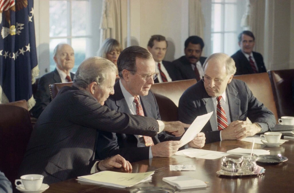 O presidente George H. W. Bush conversa com o secretário de Estado, James Baker III, e o secretário de Defesa, Dick Cheney, durante uma reunião de gabinete na Casa Branca sobre a Guerra do Golfo, no dia 17 de janeiro de 1991.