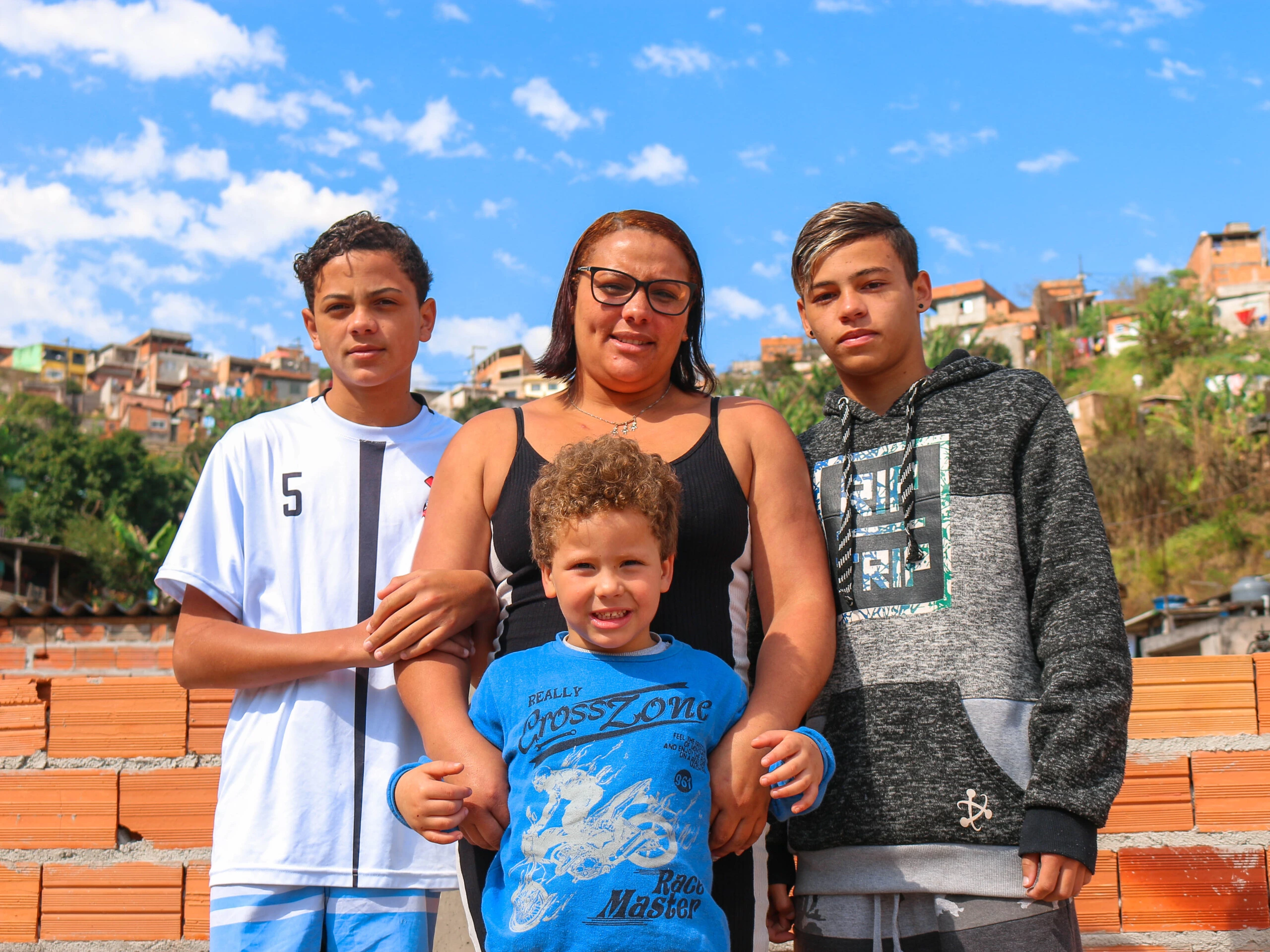 Da esquerda para a direita, Kawe, Pedro e Kawan posam para a foto na laje de casa. No meio, Tâmara, "mãe e pai" das crianças desde que o pai saiu de casa quando o caçula era recém-nascido.