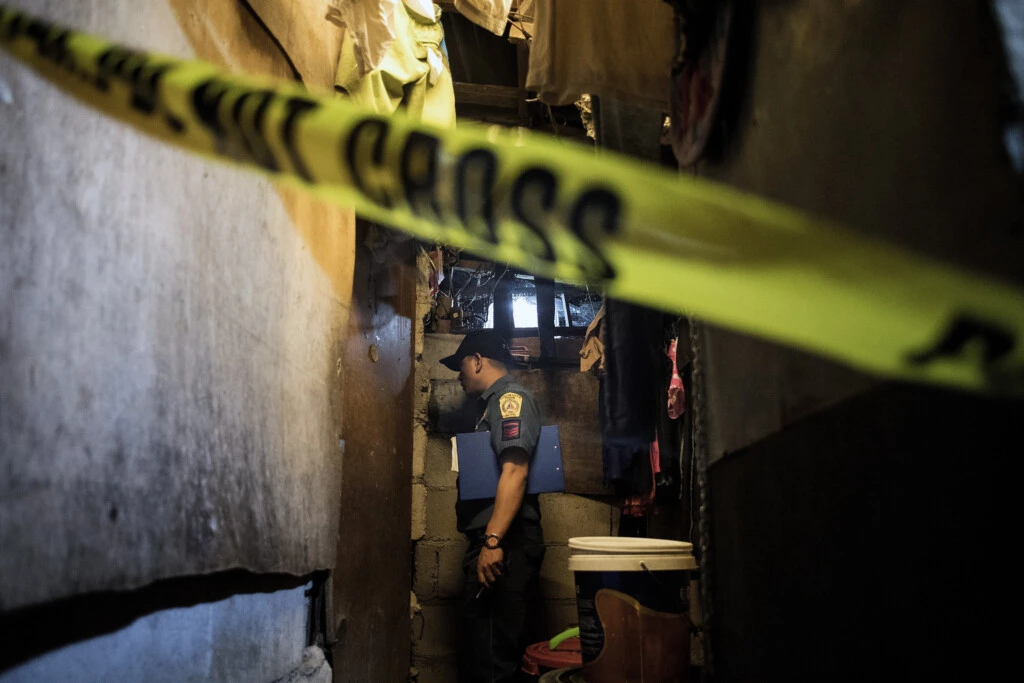 Um policial investiga uma cena de crime onde está o corpo de um suposto traficante de drogas, em uma área de favela em Manila, morto por agressores não identificados em 8 de dezembro de 2017.