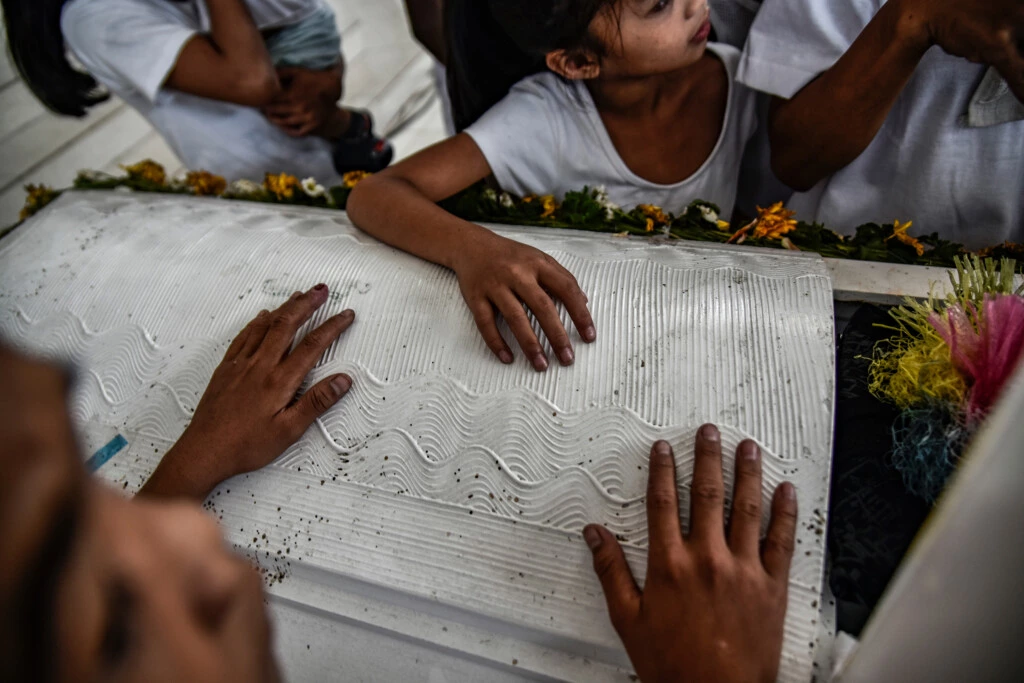 Crianças seguram o caixão de Aldrin Pineda, de 13 anos, morto a tiros por um policial, durante seu funeral em Manila, nas Filipinas, em 14 de março de 2018.