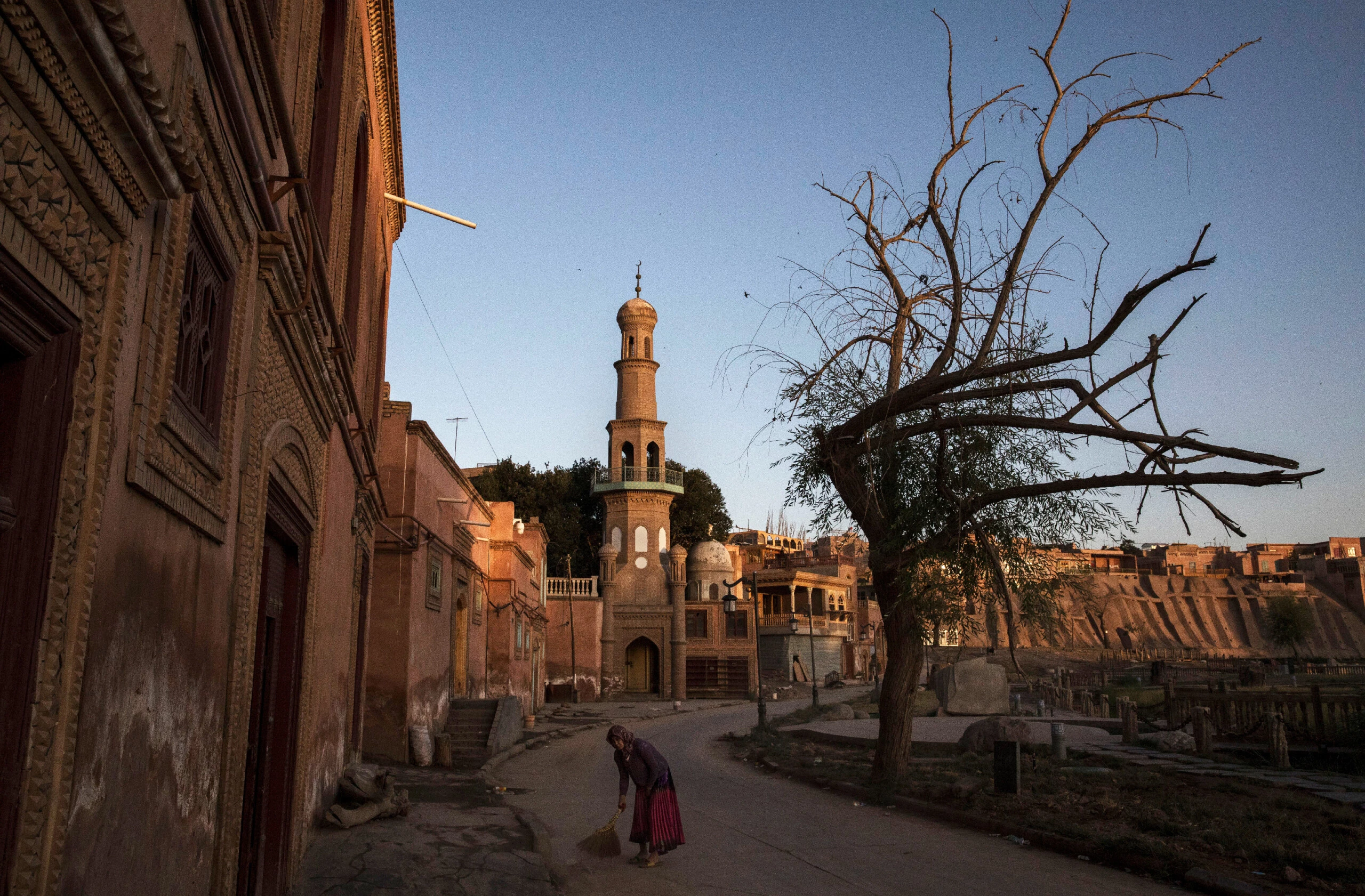 Uma mulher uigur varre o lado de fora de sua casa no dia 1º de julho de 2017, na cidade antiga de Kashgar, no extremo oeste da província de Xinjiang, na China.