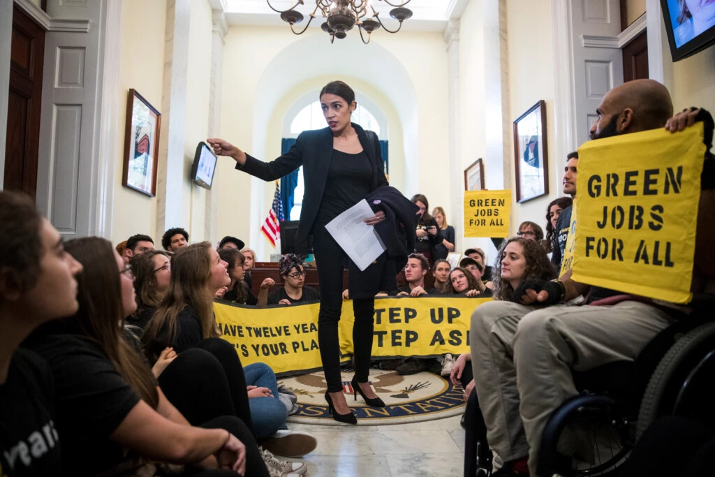 Alexandria Ocasio-Cortez fala com ativistas do movimento Sunrise Movement que protestam nos escritórios da líder da minoria da Câmara, Nancy Pelosi, em Washington D.C., em 13 de novembro.