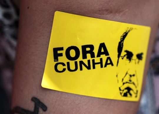 A supporter of Brazilian President Dilma Rousseff demonstrates against her possible impeachment with a sticker reading "Cunha out", referring to the president of the Brazilian Chamber of Deputies, Eduardo Cunha, in Rio de Janeiro, Brazil on December 8, 2015. Brazil's opposition took the majority of seats Tuesday on a special congressional commission that will be first up to analyze the impeachment case against President Dilma Rousseff. AFP PHOTO / YASUYOSHI CHIBA / AFP / YASUYOSHI CHIBA        (Photo credit should read YASUYOSHI CHIBA/AFP/Getty Images)
