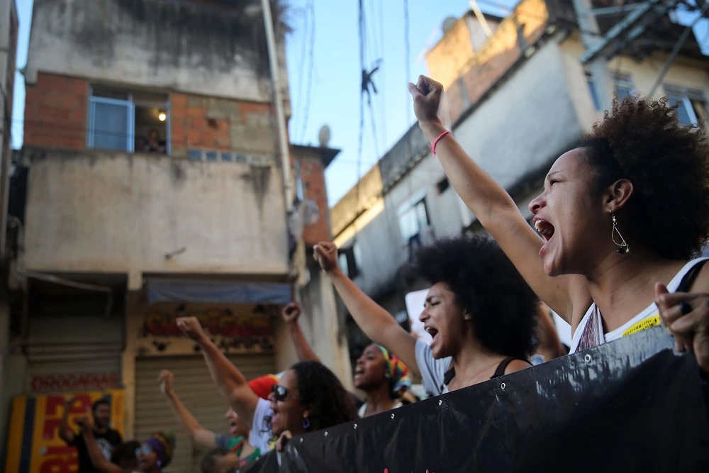 RIO DE JANEIRO, BRAZIL - AUGUST 22: Demonstrators march through the Manguinhos favela to protest against police killings of blacks on August 22, 2014 in Rio de Janeiro, Brazil. Every year, Brazil's police are responsible for around 2,000 deaths, one of the highest rates in the world. Many of the deaths in Rio involve blacks killed in favelas, also known as slums. (Photo by Mario Tama/Getty Images)