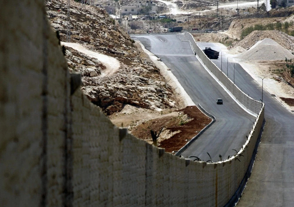 A car drives on a new segment of a highway separating Palestinian and Israeli traffic near the West Bank city of Ramallah, 12 August 2007. Once finished, the highway will connect north of the West Bank to its south, bypassing Jerusalem. The highway will be used by both Palestinians and Israelis, but on two different lanes separated by a wall of concrete. AFP PHOTO/ABBAS MOMANI (Photo credit should read ABBAS MOMANI/AFP/Getty Images)
