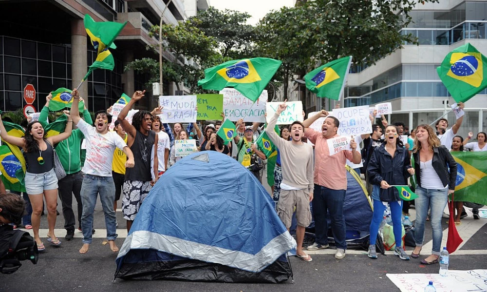 Protesters camping, since last night, in front of the residence of Rio de Janeiro's governor Sergio Cabral, in Leblon, Rio de Janeiro, shout slogans while blocking the street on June 22, 2013. Brazil girded for more street protests Saturday despite President Dilma Rousseff's conciliatory remarks pledging to improve public services and fight corruption, while warning against further violence. Her speech came a day after more than one million people marched in cities across the country to slam the huge cost of hosting next June's World Cup, put at some 15 billion dollars, while public services such as schools and hospitals are lacking.   AFP PHOTO / TASSO MARCLEO        (Photo credit should read TASSO MARCELO/AFP/Getty Images)