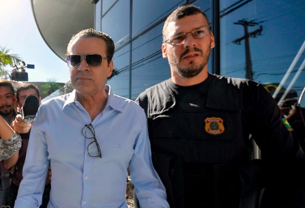 Former Brazil's Tourism Minister Henrique Eduardo Alves (L) is escorted by a Federal Police agent after being arrested at his residence in Natal, Rio Grande do Norte state, Northeast of Brazil, on June 6, 2017.Alves is accused of being involved in corruption during the construction of one of the ten stadiums Brazil buildt for the 2014 FIFA World Cup, the Arena das Dunas Stadium in Natal. / AFP PHOTO / Tribuna do Norte / MAGNUS NASCIMENTO / Brazil OUT / RESTRICTED TO EDITORIAL USE - MANDATORY CREDIT "AFP PHOTO /Tribuna do Norte /HO " - NO MARKETING - NO ADVERTISING CAMPAIGNS - DISTRIBUTED AS A SERVICE TO CLIENTS (Photo credit should read MAGNUS NASCIMENTO/AFP/Getty Images)