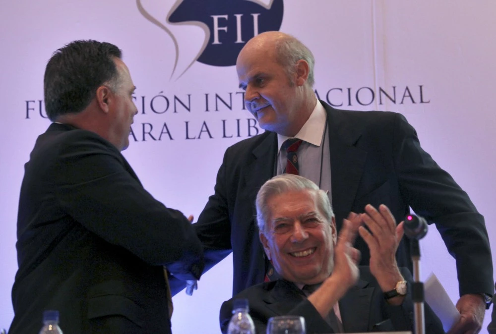 Alejandro Chafuen, of the Atlas Economic Research Foundation, back right, shakes hands with Rafael Alonzo, of Venezuela's Freedom Center for  Economic Studies, CEDICE, left, as Peruvian writer Mario Vargas Llosa applauds during the opening of the "Freedom and Democracy" international  forum in Caracas, Thursday, May 28, 2009.(AP Photo/Ariana Cubillos)