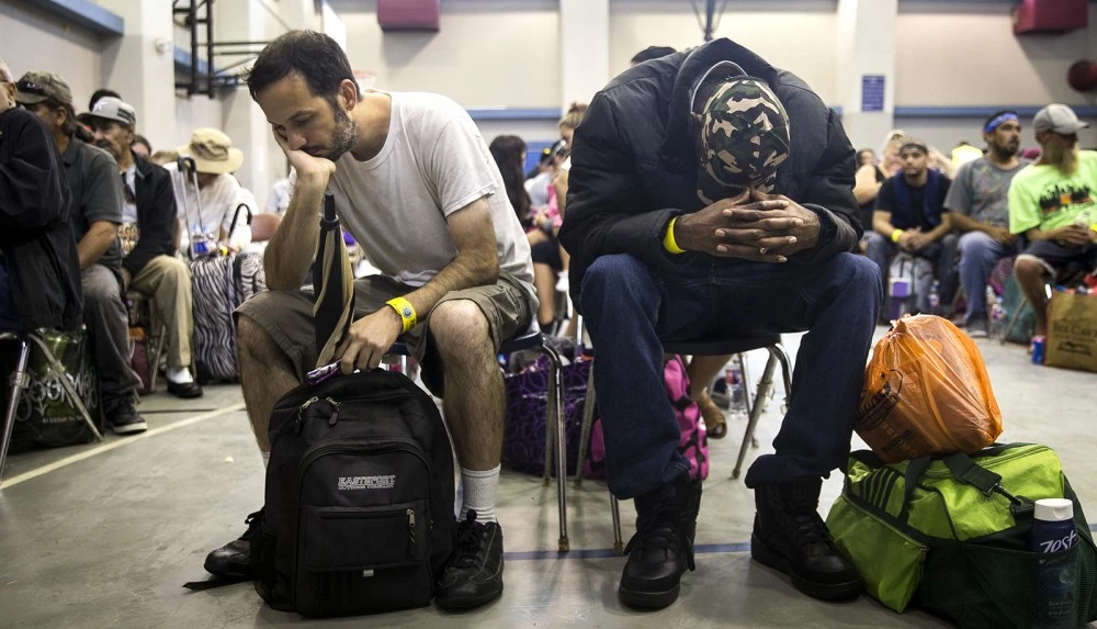 People rest while waiting to board a bus headed for San Antonio at an evacuation center in Corpus Christi, Texas on Friday, Aug. 25, 2017. Hundreds of residents of the Corpus Christi area boarded buses Friday to be transported to a shelter in San Antonio as Hurricane Harvey is expected to make landfall on the Texas coast Friday night or early Saturday morning. (Nick Wagner/Austin American-Statesman via AP)