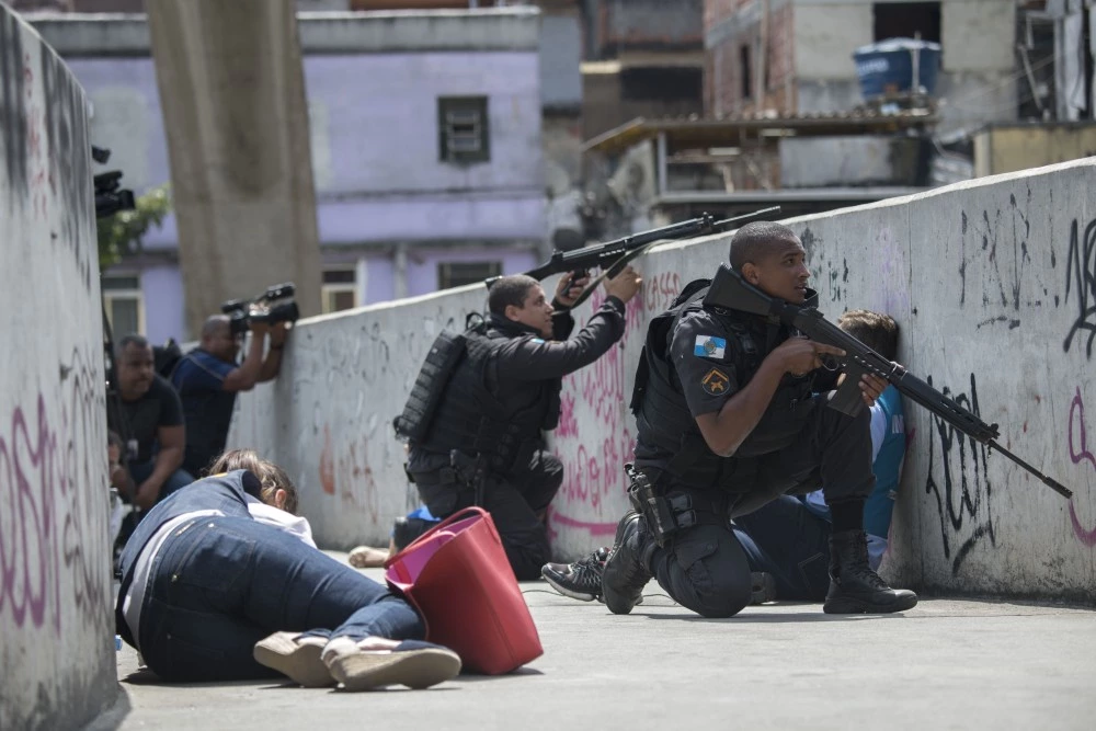 Policemen and journalists take cover during an operation to fight heavily armed drug traffickers at the Rocinha favela in Rio de Janeiro, Brazil, on September 22, 2017. Brazilian soldiers were sent to help Rio de Janeiro police fight heavily armed drug traffickers who have taken over much of the biggest shantytown in the country, the Rocinha favela. Local media reported intense shooting between police and criminals early Friday at Rocinha, where approximately 70,000 people live in a teeming collection of small homes on steep hillsides overlooking western Rio. / AFP PHOTO / Mauro PIMENTEL (Photo credit should read MAURO PIMENTEL/AFP/Getty Images)