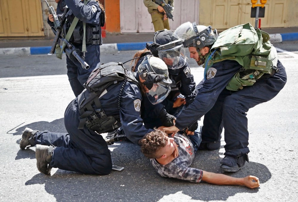Israeli forces arrest a Palestinian youth during clashes between demonstrators and security forces in the city of Hebron in the Israeli-occupied West Bank, on July 28, 2017, as protests erupt in support of the Al-Aqsa mosque compound after Israeli police barred men under 50 from Friday prayers in the Old City of Jerusalem.Palestinians held mass prayers outside of a sensitive Jerusalem holy site after Israeli police barred men under 50 from entering following two weeks of tensions and deadly unrest. Despite fears of violent clashes around the Haram al-Sharif compound, known to Jews as the Temple Mount, the area was largely calm following Friday's midday prayers. / AFP PHOTO / HAZEM BADER (Photo credit should read HAZEM BADER/AFP/Getty Images)