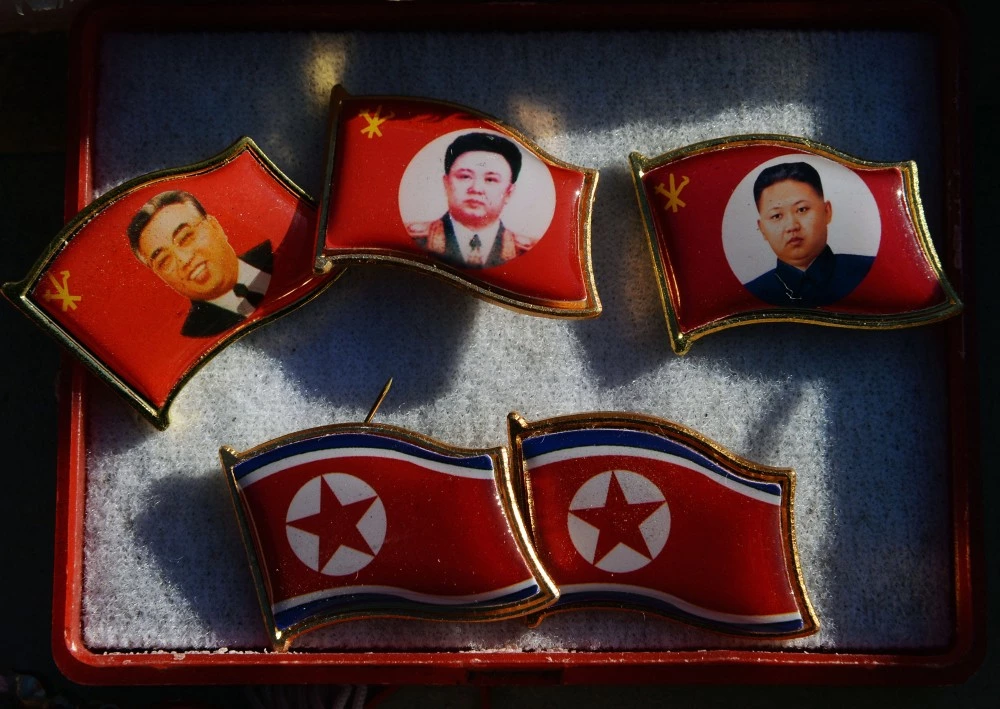 Badges showing late North Korean leaders (L-R) Kim Il Sung and Kim Jong Il and new leader Kim Jong-Un for sale by a street vendor in the Chinese border town of Dandong on the second anniversary of the death of former leader Kim Jong-Il, December 17, 2013.  North Korean leader Kim Jong-Un presided over a major remembrance ceremony on the second anniversary of the death of his father and former leader Kim Jong-Il. The meeting came days after the shock execution of Kim Jong-Un's uncle and one-time political mentor, Jang Song-Thaek -- a purge that raised questions about the stability of the current regime in Pyongyang.        AFP PHOTO/Mark RALSTON        (Photo credit should read MARK RALSTON/AFP/Getty Images)