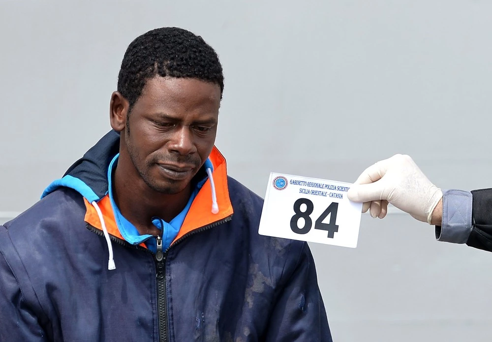Italian police officers identify a migrant suspected to be a smuggler after disembarking off the Italian Guardia Costiera vessel Fiorillo at the Sicilian harbour of Catania on April 24, 2015. EU leaders gathered in Brussels on April 23 considered launching a military operation against human traffickers in Libya, in a bold effort to halt the deadly flow of refugees trying to reach Europe by sea. AFP PHOTO / ALBERTO PIZZOLI        (Photo credit should read ALBERTO PIZZOLI/AFP/Getty Images)