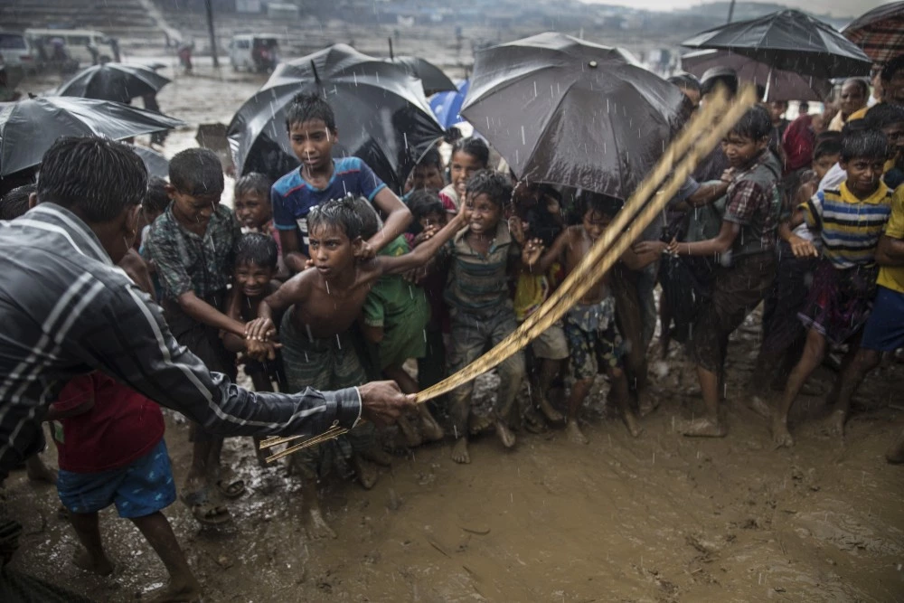 THAINKHALI, BANGLADESH - OCTOBER 7: A man hits anxious Rohingya children with a cane as things get out of control during a humanitarian aid distribution while monsoon rains continue to batter the area causing more difficulties October 7, Thainkhali camp, Cox's Bazar, Bangladesh. Well over half a million Rohingya refugees have fled into Bangladesh since late August during the outbreak of violence in Rakhine state causing a humanitarian crisis in the region with continued challenges for aid agencies. (Photo by Paula Bronstein/Getty Images)
