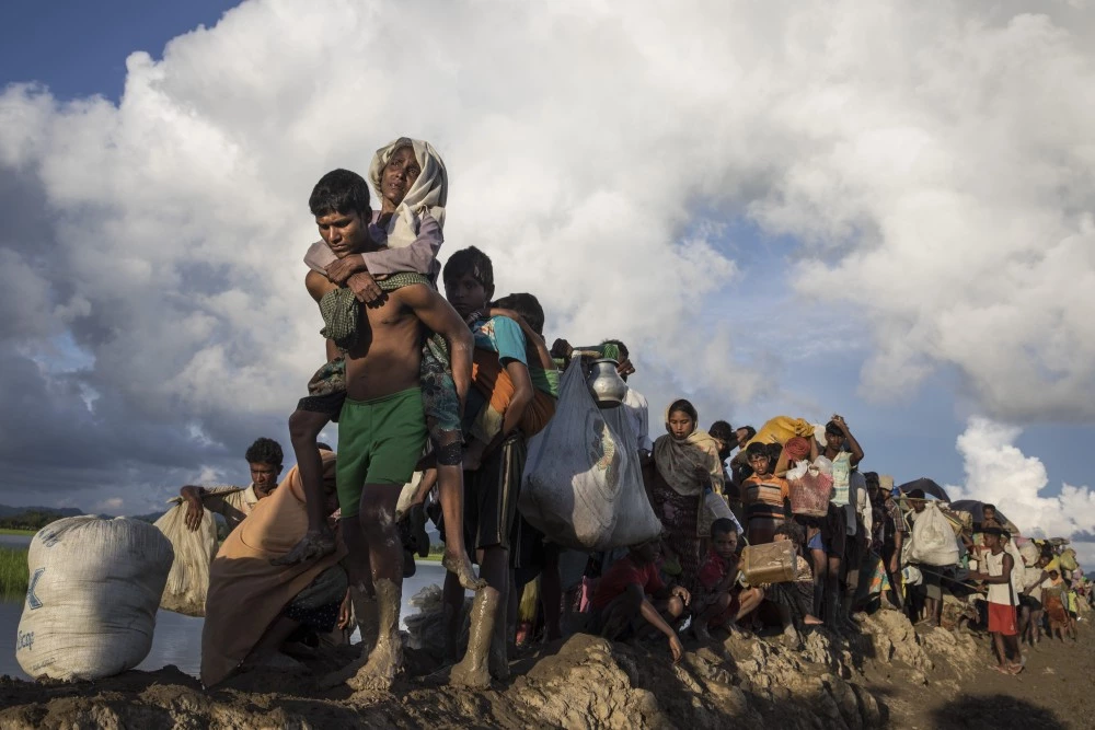 PALONG KHALI, BANGLADESH - OCTOBER 9: Thousands of Rohingya refugees fleeing from Myanmar walk along a muddy rice field after crossing the border in Palang Khali, Cox's Bazar, Bangladesh.  Well over a half a million Rohingya refugees have fled into Bangladesh since late August during the outbreak of violence in Rakhine state causing a humanitarian crisis in the region with continued challenges for aid agencies. (Photo by Paula Bronstein/Getty Images)